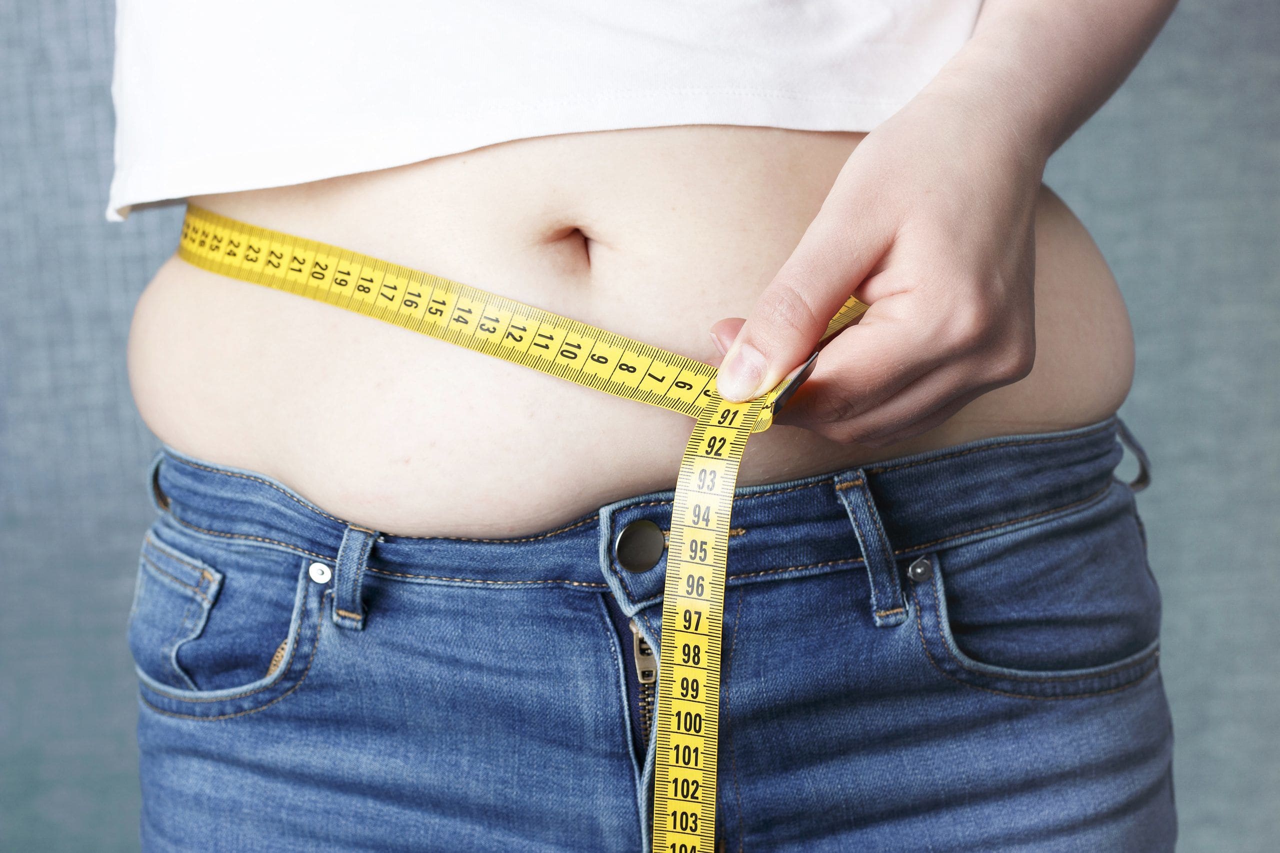 Растет живот у женщин после 40 причины. Лишний вес. Девушка меряет талию. Измерить талию у женщин.